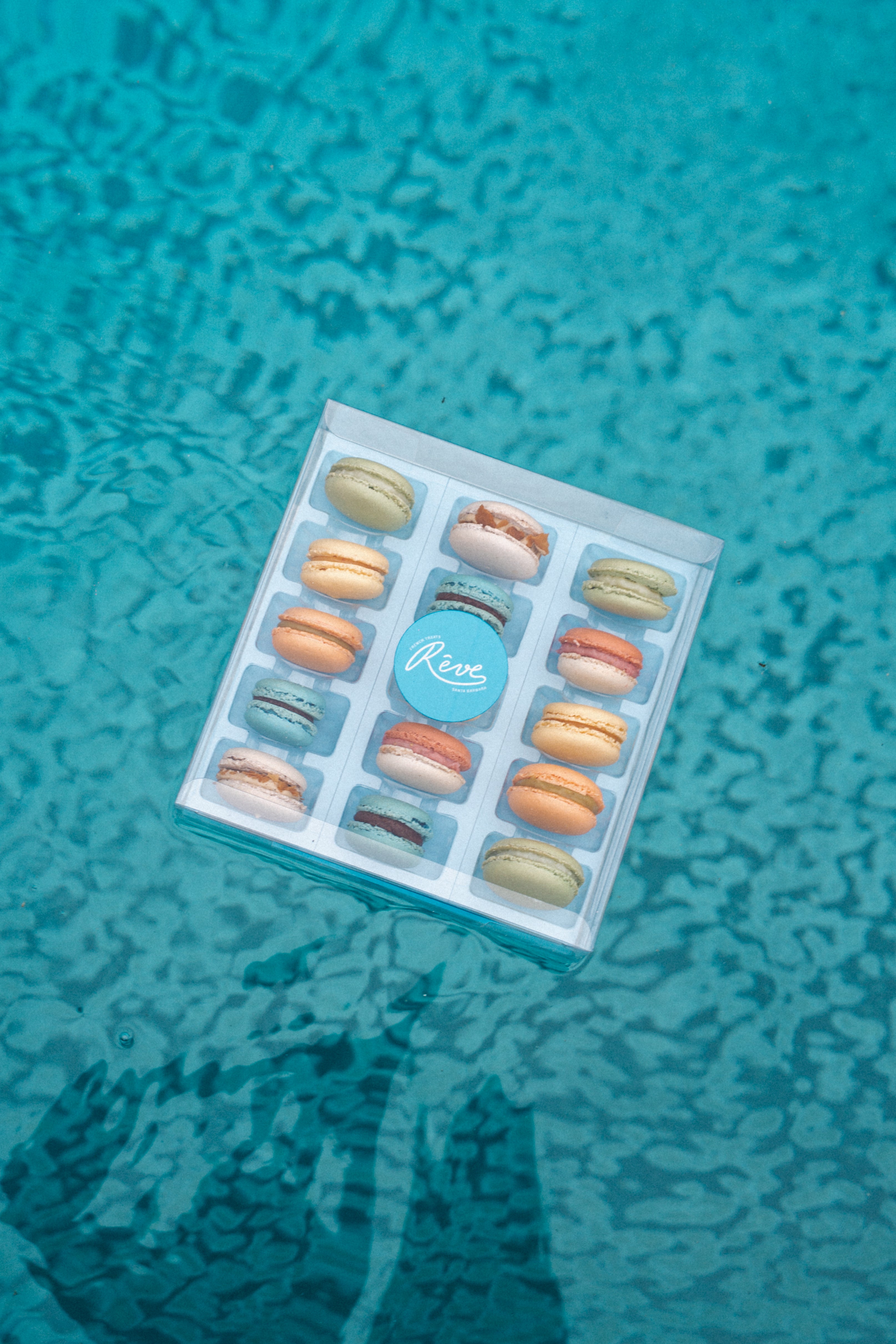 Box of macarons floating on a blue textured surface