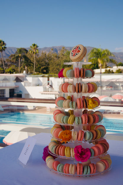 Colorful macaron tower with floral decorations on a table at The Santa Barbara Coral Casino poolside.