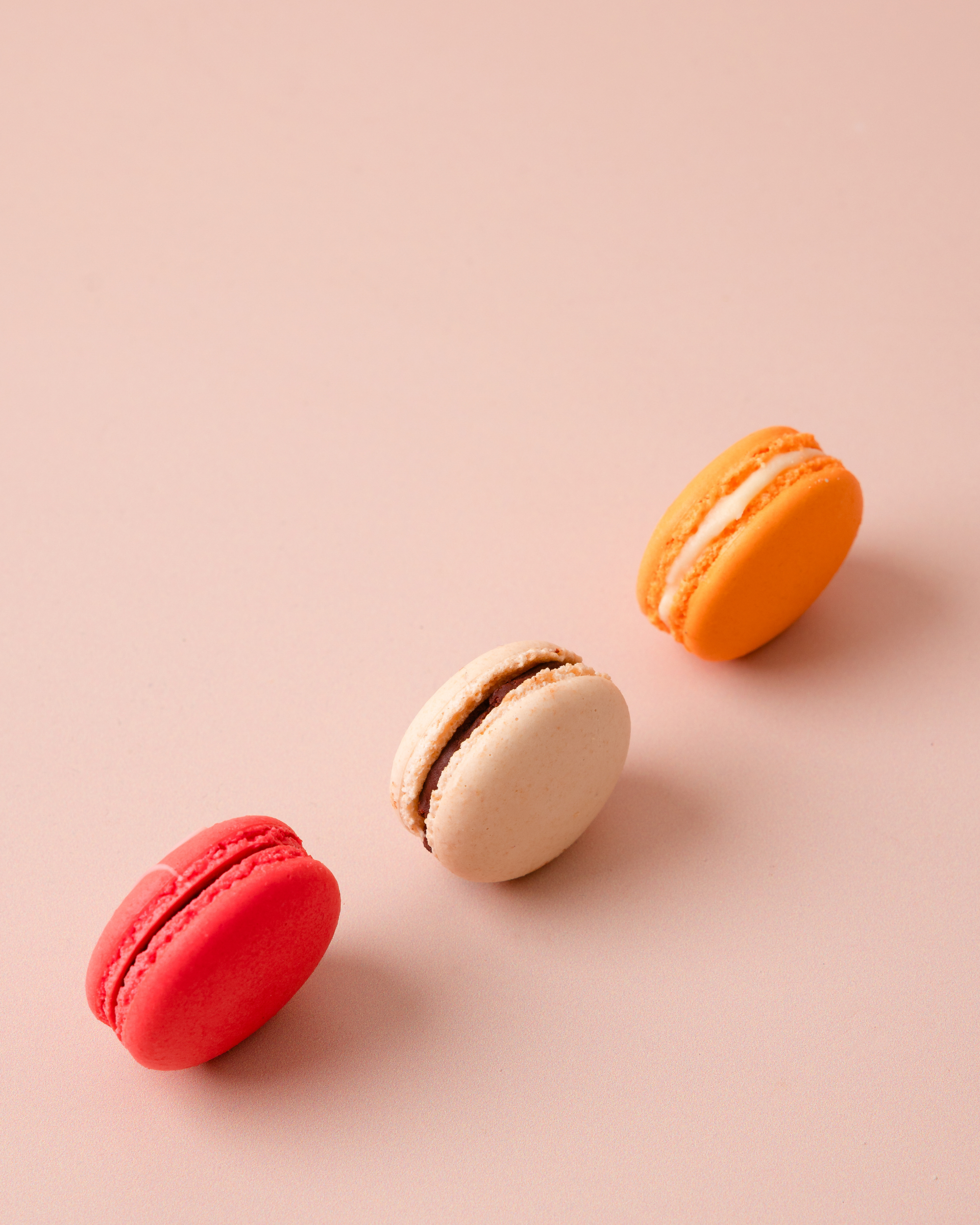 Three colorful macarons on a beige background