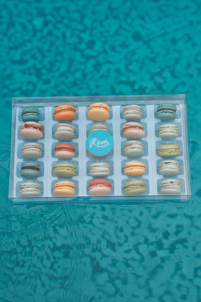 Box of 25 macarons floating on a blue pool