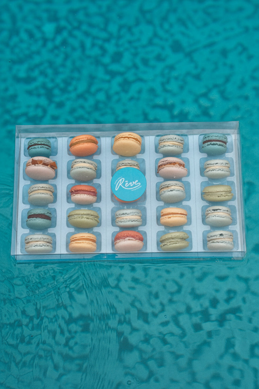 Box of 25 macarons floating on a blue pool