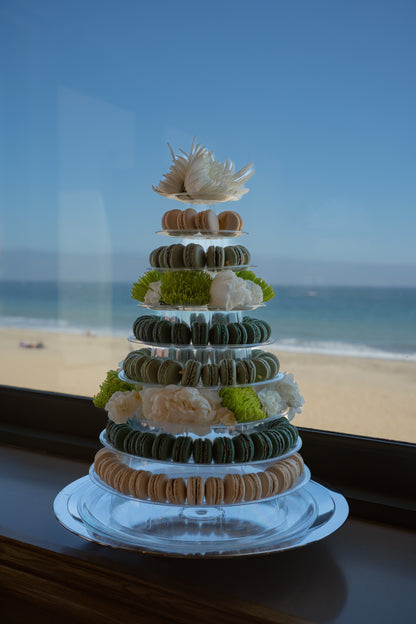 Luxury dessert Multi-tiered wedding Macaron tiered display with decorative elements on a clear stand, set against a beach backdrop in Santa Barbara SoCal