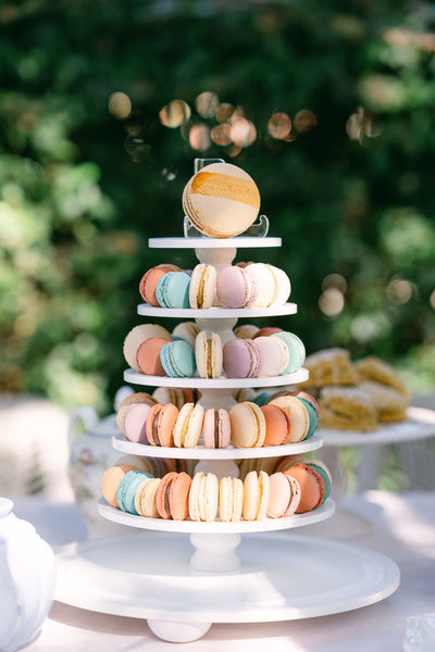 4-tiered macaron tower with colorful macarons on a white stand outdoors at a bridal shower