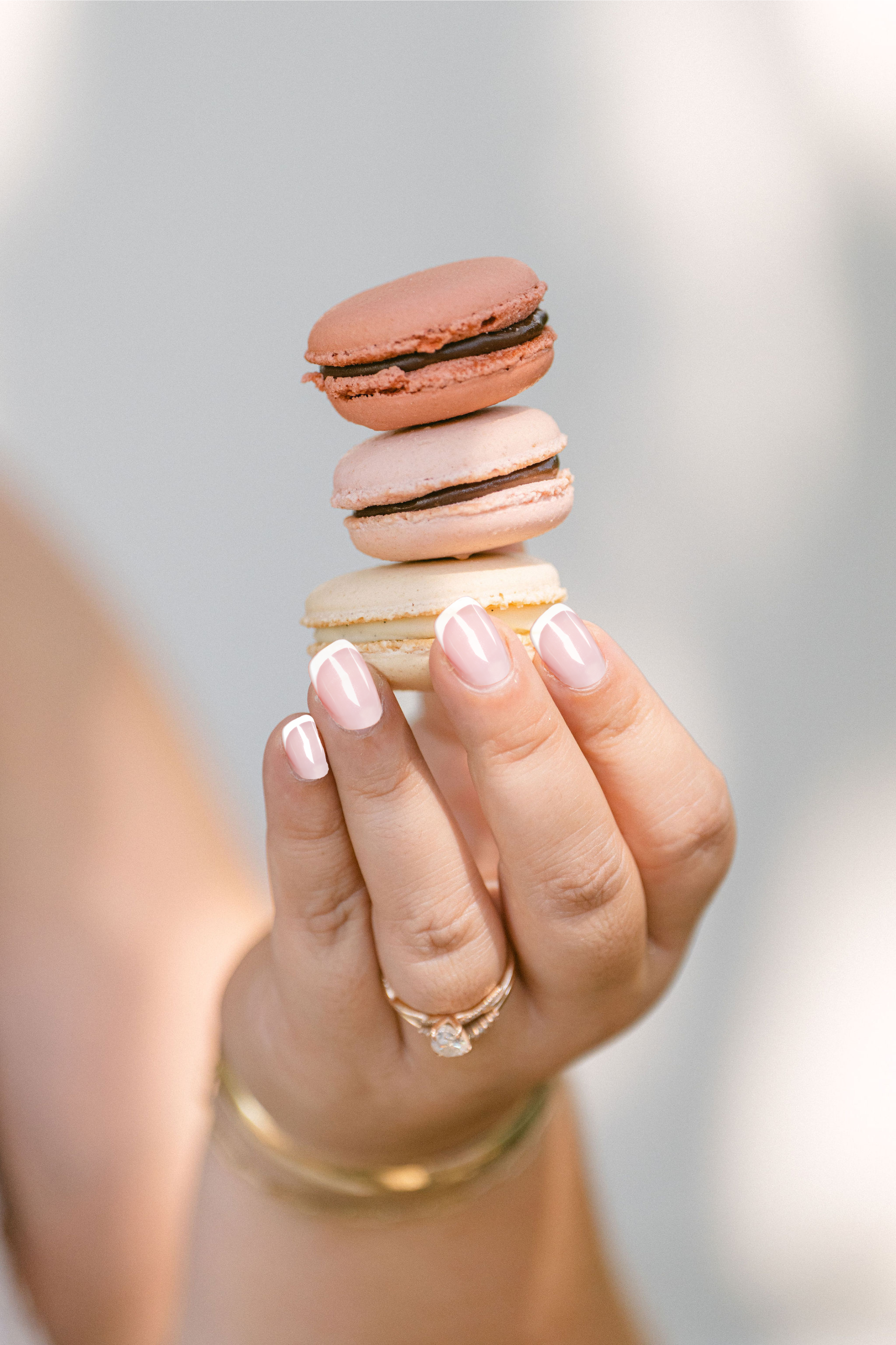 Hand holding a stack of colorful macarons against a blurred background
